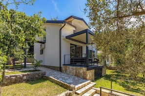 A modern house with a stone pathway leading to a covered outdoor seating area. - Beachside House Lara (Omisalj)