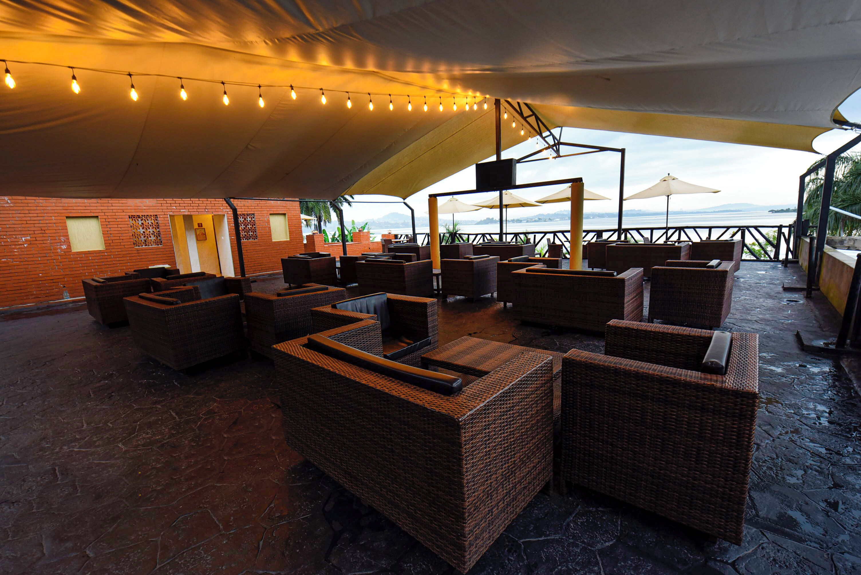 An outdoor seating area with wicker furniture, a brick wall, and a view of the sea.