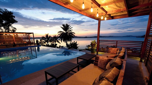 A poolside area with a wooden pergola, lounge seating, and a view of the water. - Divine Resort & Spa (Kampala)