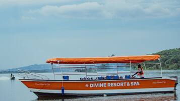 Un bote con toldo naranja y una persona con chaleco salvavidas, identificado como 'DIVINE RESORT & SPA'.