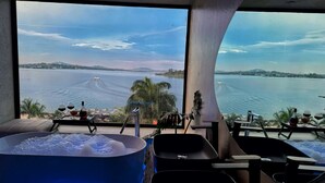 A room with a large bathtub, a sink, and a window overlooking a body of water. - Divine Resort & Spa (Kampala)