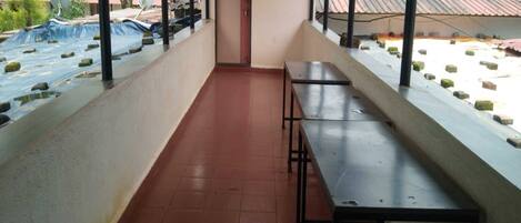 A covered outdoor area with tiled flooring, a few benches, and a door leading to another space.