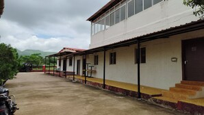 Rakennus, jossa on katettu ulkoalue, portaikko, joka johtaa ovelle, ja pysäköity ajoneuvo.