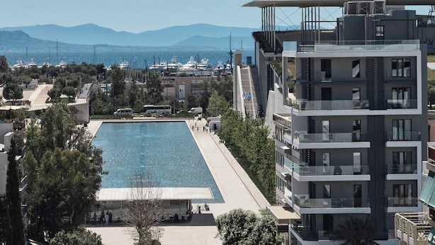 A modern building with a rooftop pool and a view of the sea and mountains. - AVA Hotel & Residences Athens Riviera (Kallithea)