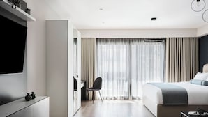 A modern hotel room with a large bed, a desk, and a TV. - AVA Hotel & Residences Athens Riviera (Kallithea)