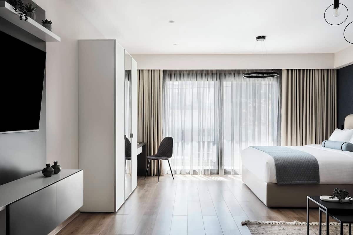 Una habitación de hotel moderna con una cama grande, un escritorio y un televisor.