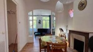 A spacious room with a wooden floor, a dining table with chairs, a fireplace, and a large window allowing natural light. - La parenthèse Arcachonnaise" apartment (Arcachon)