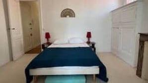 A bedroom with a bed, two bedside tables with lamps, a door, and a wall-mounted shelf. - La parenthèse Arcachonnaise" apartment (Arcachon)