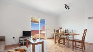 Ein Wohnzimmer mit einer Couch, einem Couchtisch, einem Fernseher und einem Essbereich mit Tisch und Stühlen.