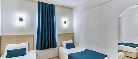 A hotel room with two beds, a large mirror, and a window with curtains.