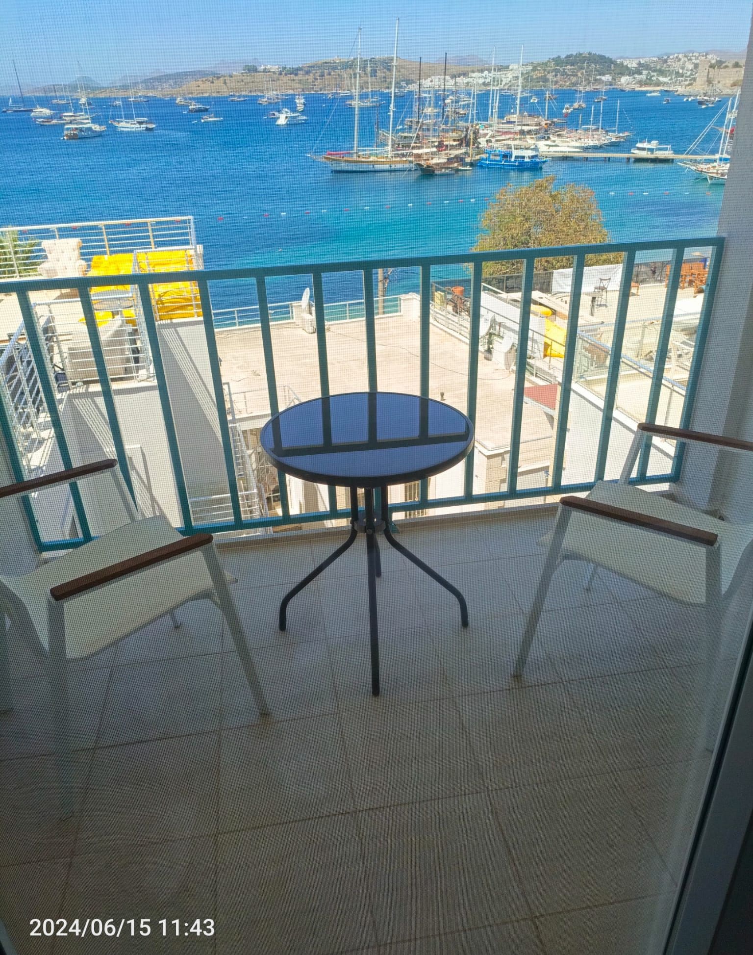 A balcony with a round table and a view of a marina with boats.