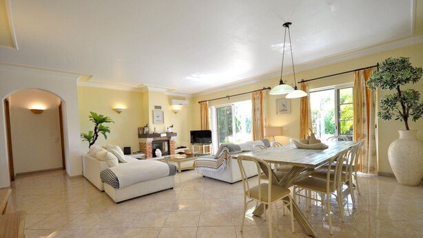 A spacious living area with a fireplace, a dining table, and comfortable seating. - Villa in Vilamoura near Falésia Beach (Quarteira)
