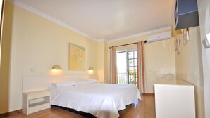 A bedroom with a bed, bedside table, and a small white cabinet. - Villa in Vilamoura near Falésia Beach (Quarteira)