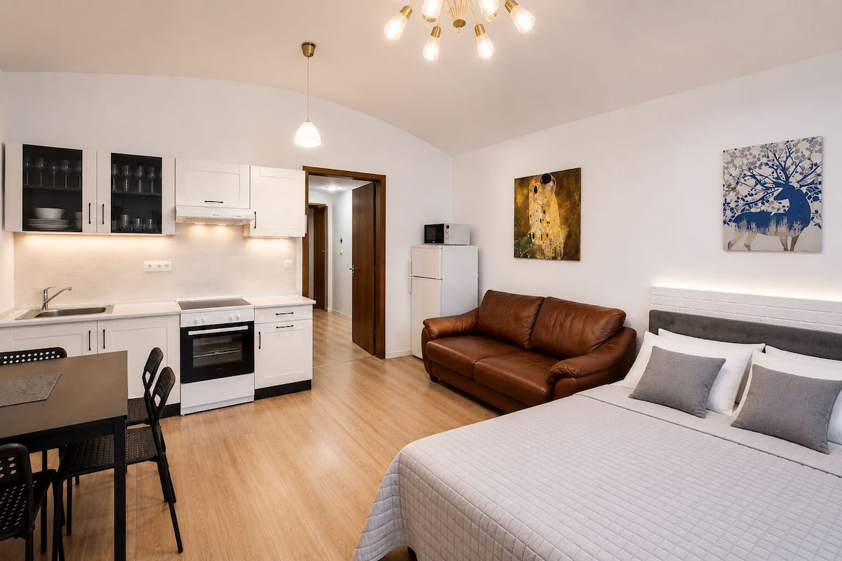 A compact living space with a kitchenette, a dining area, a sofa, and a bed.