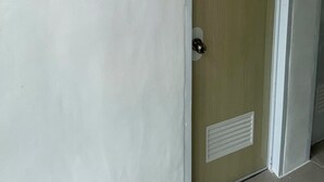 Una porta chiusa con stipite bianco, una serratura e una bocchetta di ventilazione.