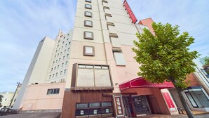 Un edificio de hotel de varios pisos con un toldo rojo y el nombre del hotel.