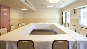 Una sala de conferencias con una larga mesa, sillas, una puerta y ventanas.
