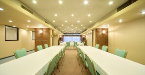 A conference room with long tables and chairs, a projector screen, and a view of the outdoors. - Hotel Pearl City Morioka (Morioka)