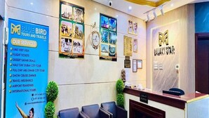 A hotel reception area with a blue wall displaying services, a chandelier, and framed pictures. - GALAXY STAR HOTEL L.L.C (Dubai)