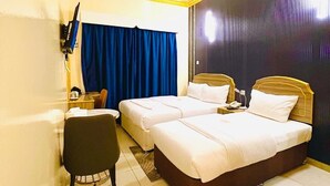 A hotel room with two beds, a desk, a chair, and a TV mounted on the wall. - GALAXY STAR HOTEL L.L.C (Dubai)
