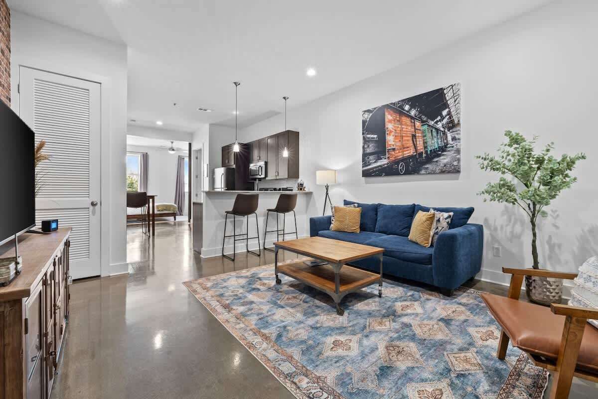 A modern living room with a blue sofa, a coffee table, and a patterned rug.