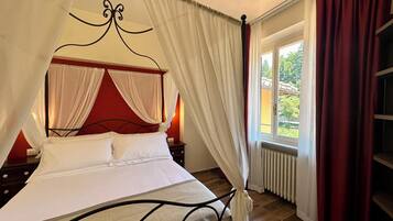 A four-poster bed with white linens, a red headboard, and a canopy.