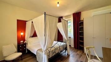A bedroom with a four-poster bed, a nightstand, a chair, a wardrobe, and a radiator.