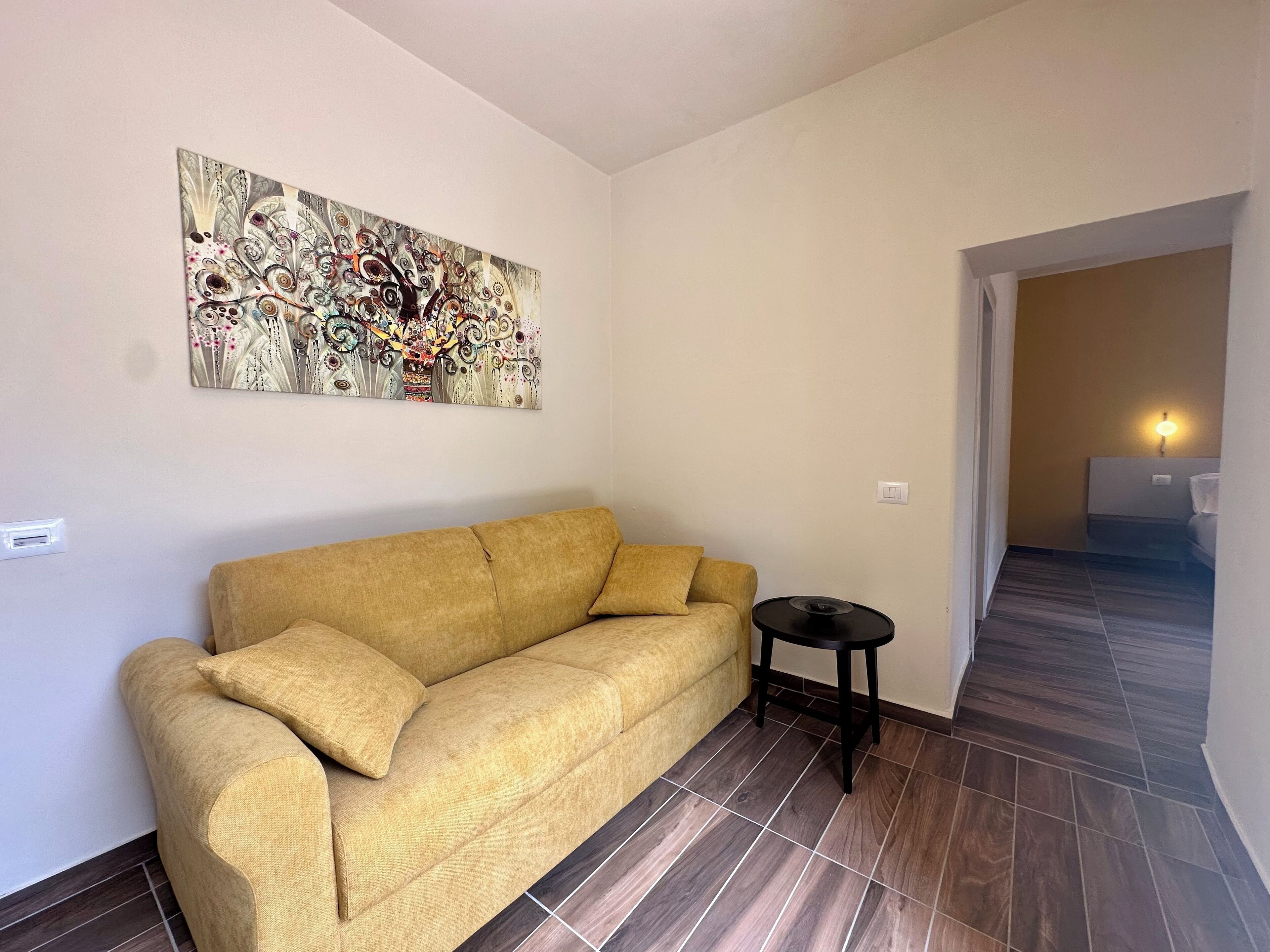 Een woonkamer met een bank, een bijzettafeltje en een decoratief kunstwerk.