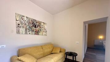 Een woonkamer met een bank, een bijzettafeltje en een decoratief kunstwerk.