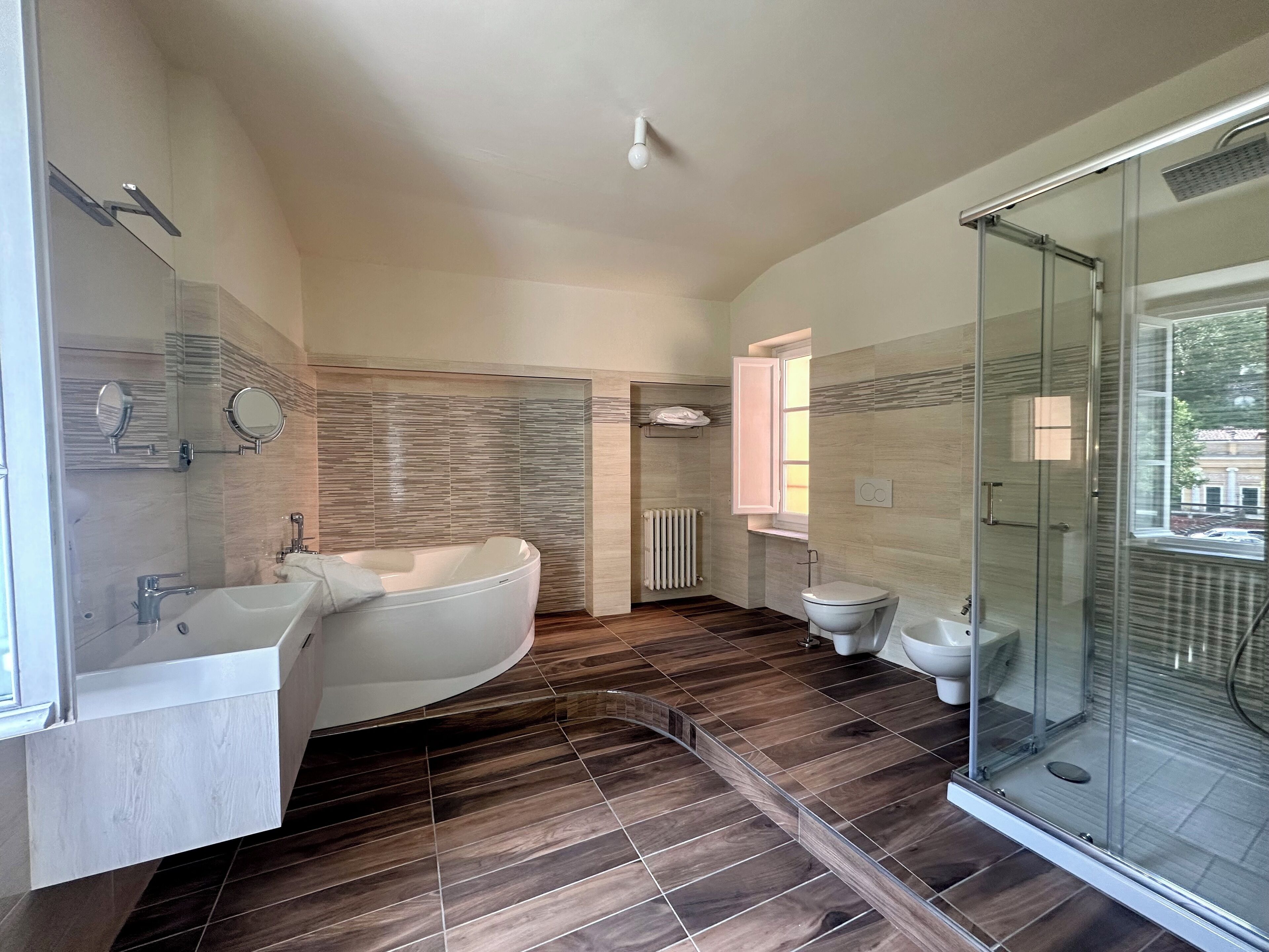 A modern bathroom with a freestanding bathtub, a glass-enclosed shower, and a toilet.