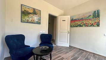 Una habitación con dos sillones azules, una mesita negra y dos cuadros en las paredes.
