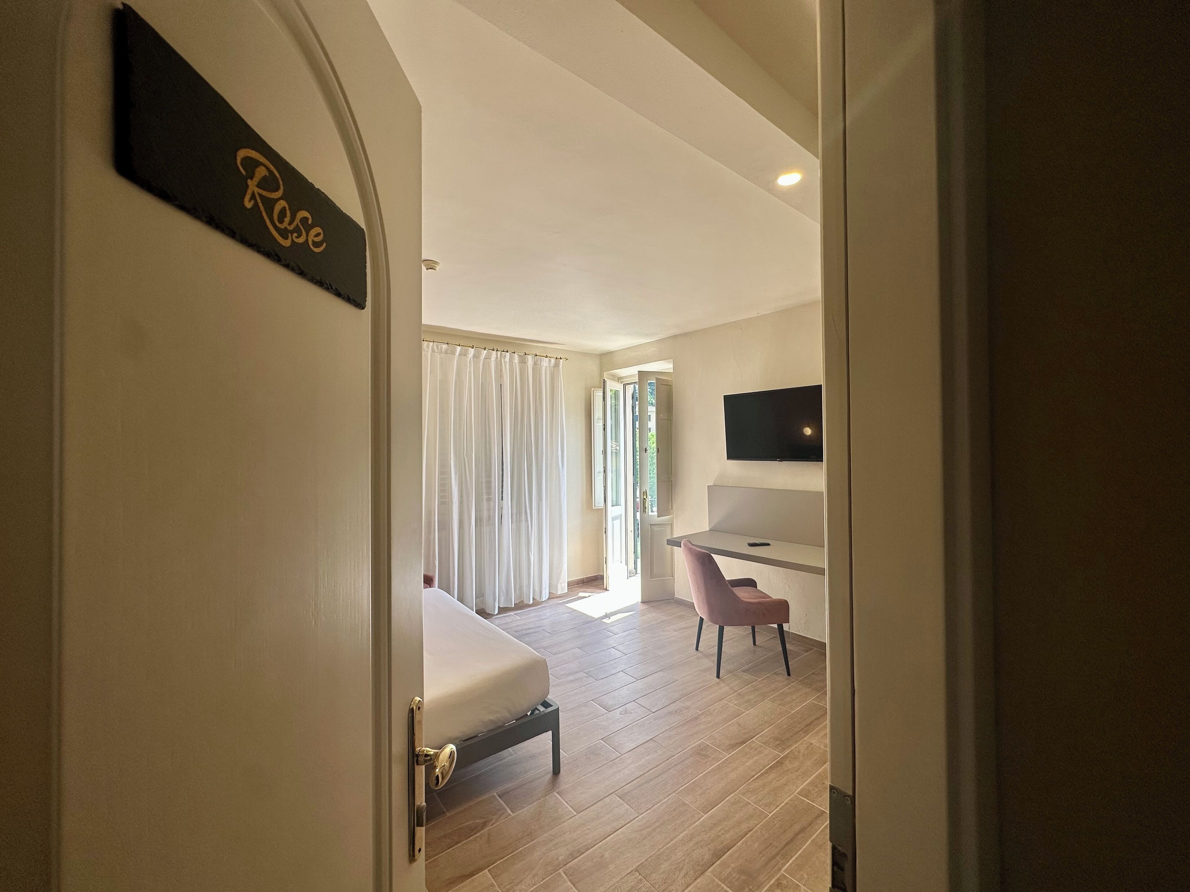 Une chambre d’hôtel équipée d’un lit, d’un bureau, d’une chaise et d’un téléviseur fixé au mur.