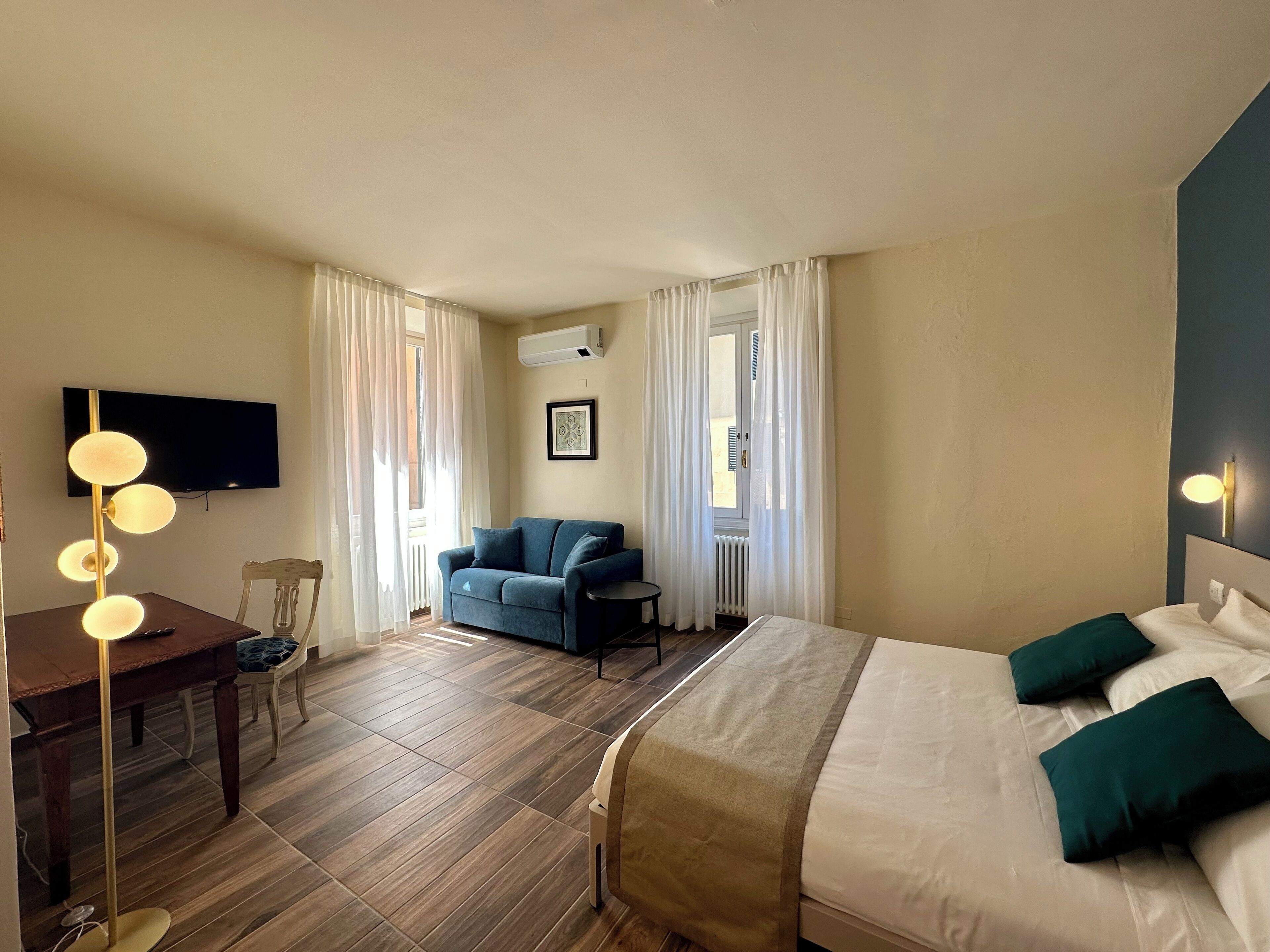 Ein Hotelzimmer mit Bett, Schreibtisch, Stuhl, Fernseher und einem Fenster mit Vorhängen.