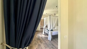 Ein Schlafzimmer mit einem Bett, einem Baldachin und einem teilweise geöffneten Vorhang.