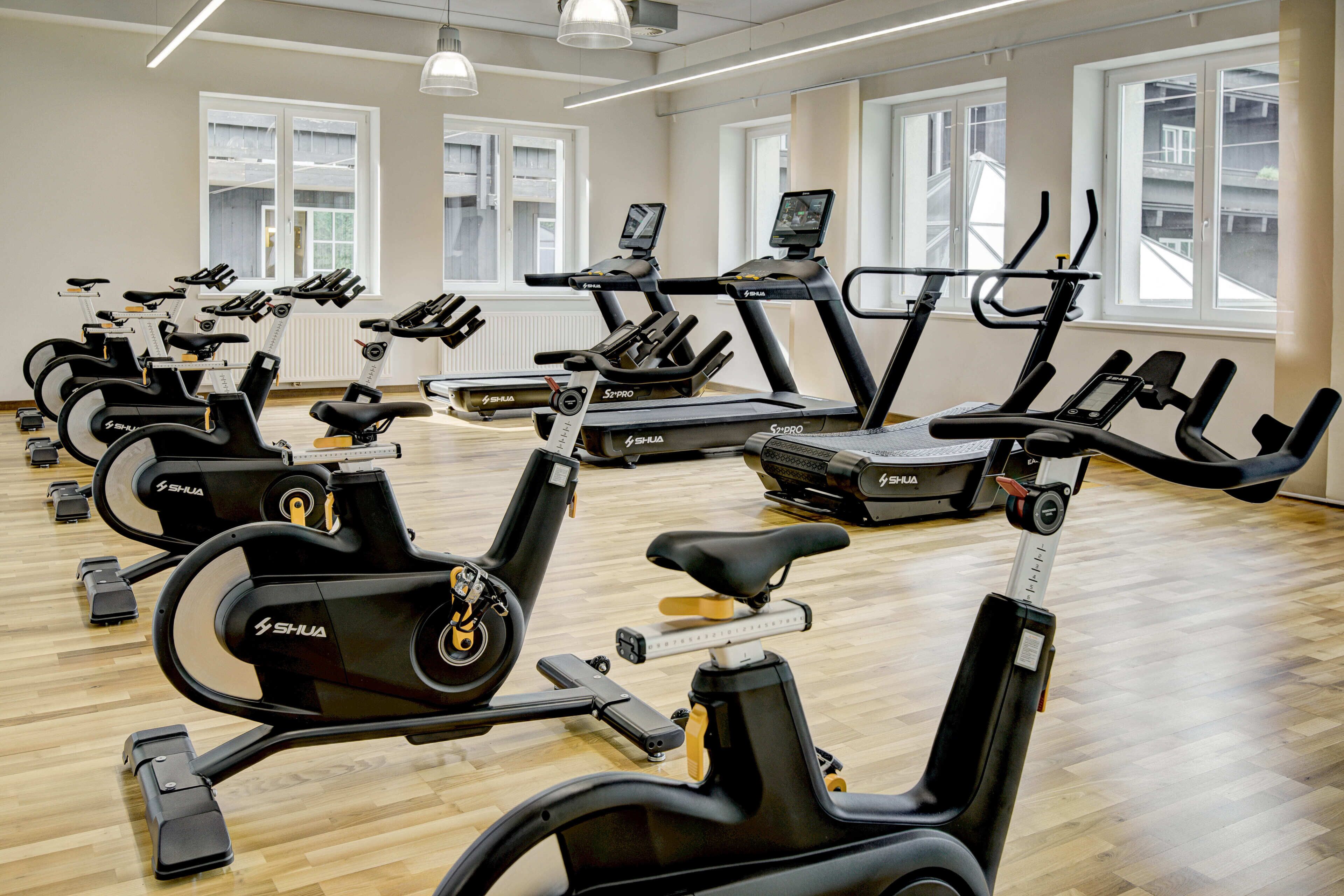Un gimnasio con varias máquinas de ejercicio, incluyendo bicicletas estáticas y cintas de correr, dispuestas en filas.