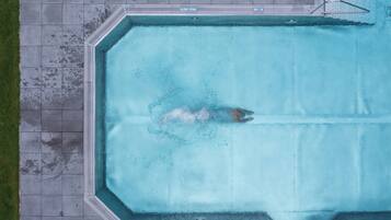 Una piscina techada, una piscina al aire libre de temporada, sombrillas