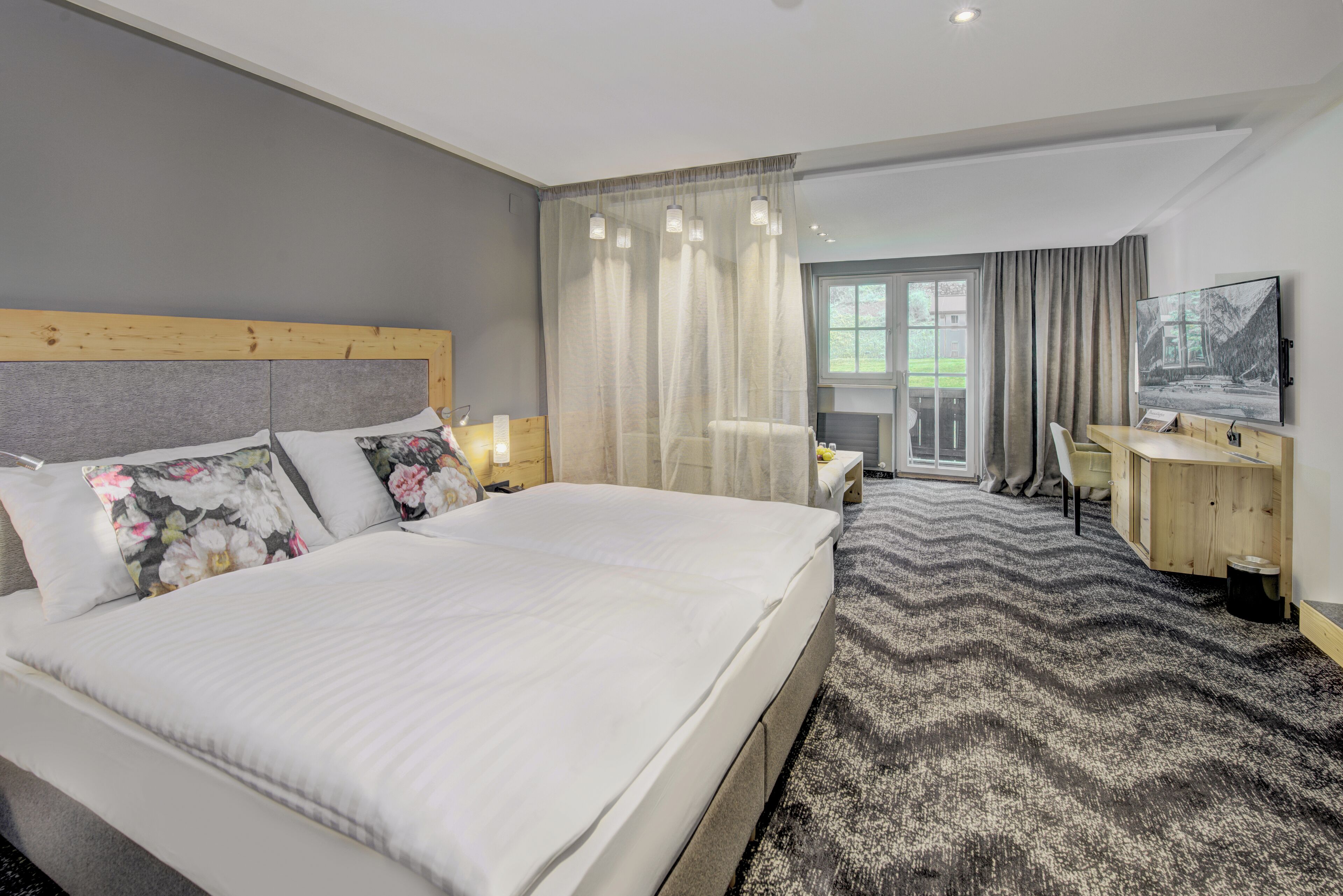 A modern hotel room with a large bed, a desk, and a television.