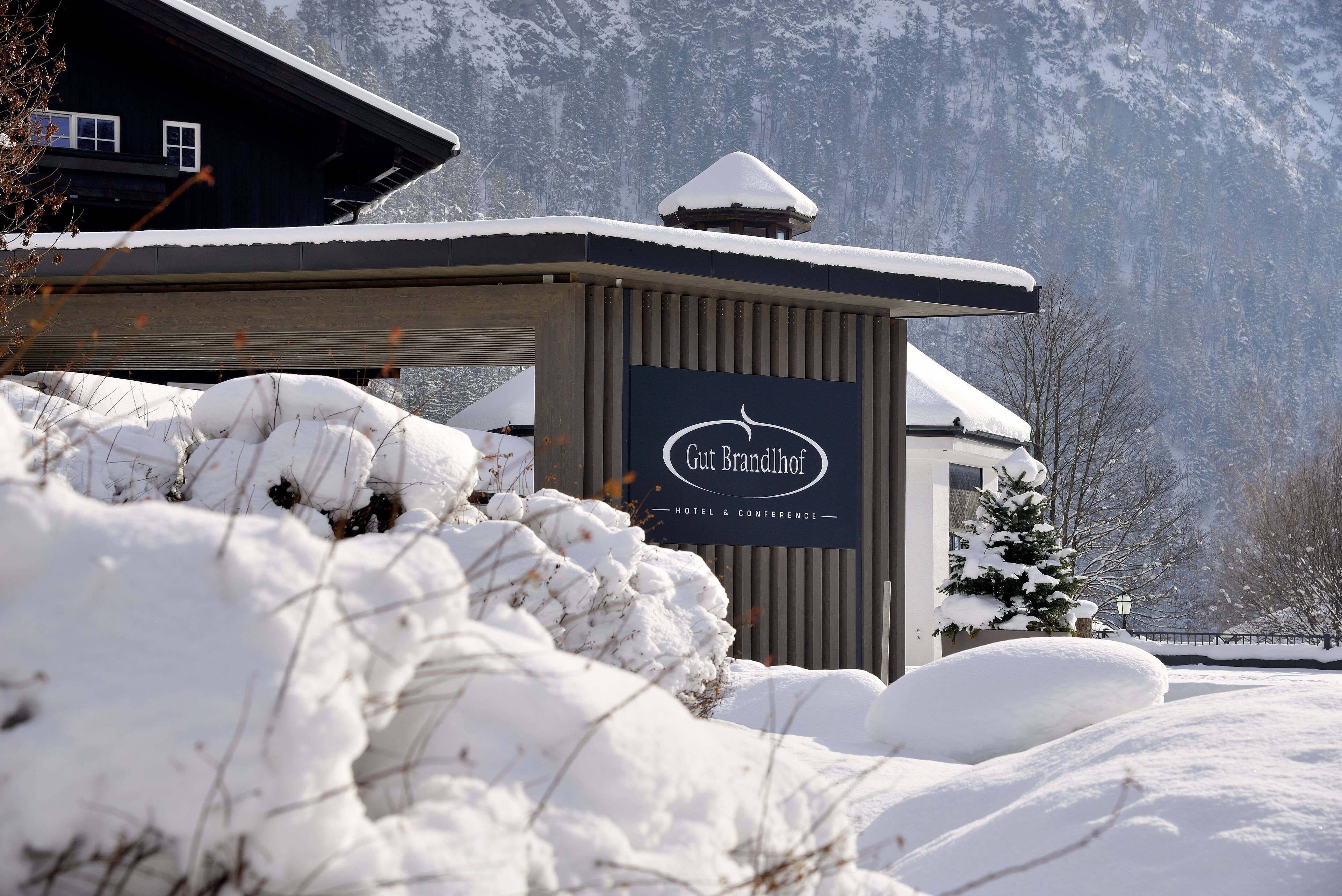 A snow-covered building with a sign reading "Gut Brandhof Hotel & Conference."