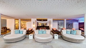 Un'ampia hall con tre zone salotto rotonde, un soffitto alto con decorazioni traforate e un arredamento moderno.