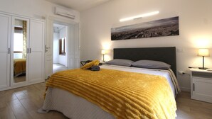 Une chambre à coucher comprenant un lit, une table de chevet, une lampe, un tableau au mur et une armoire.