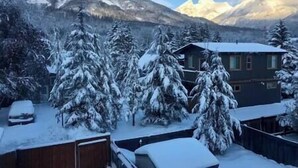 Een bergchalet met met sneeuw bedekte bomen en uitzicht op besneeuwde bergtoppen.