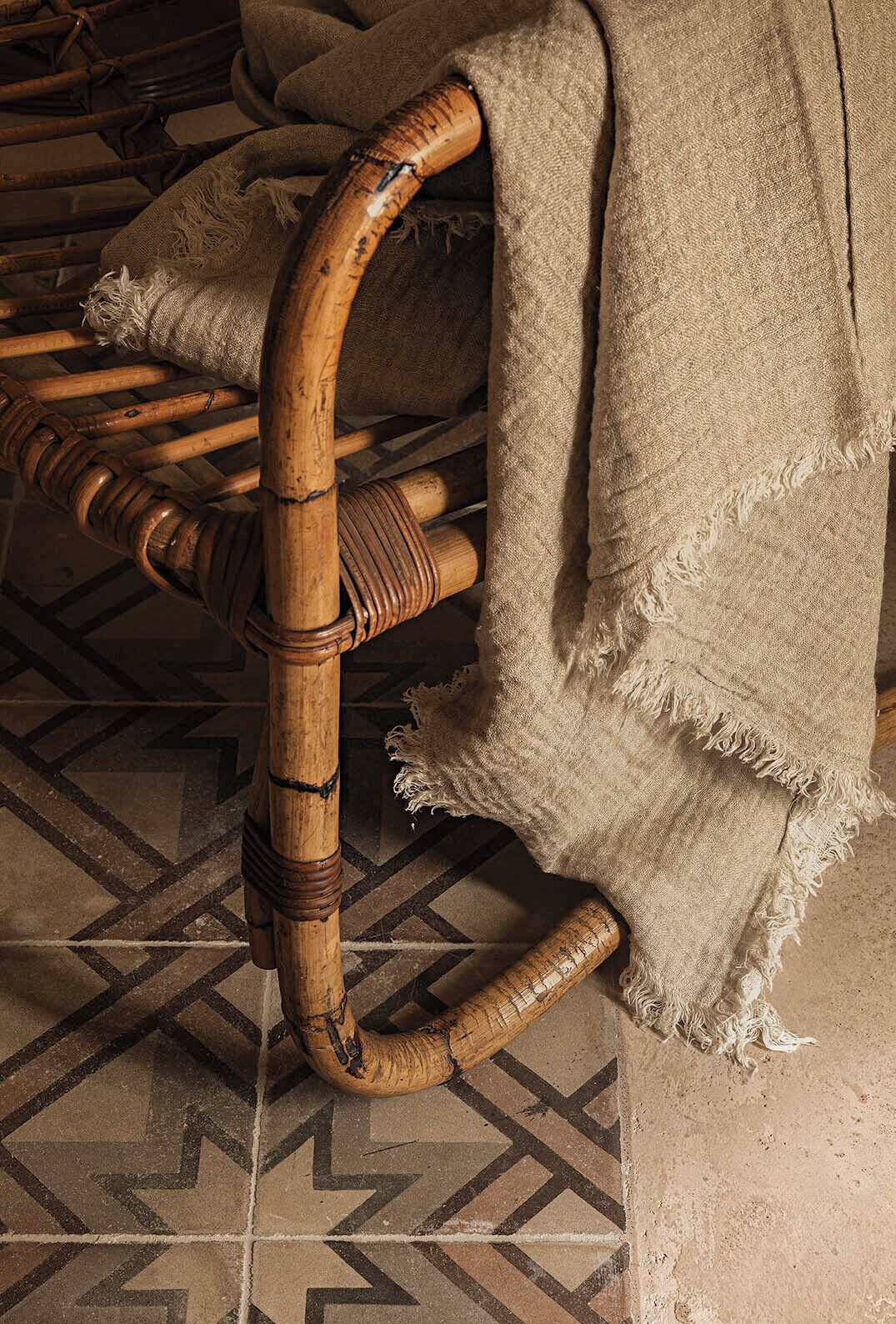 A wicker chair with a wooden frame and a frayed fabric cover.