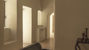 A spacious interior with a sofa, a table with a decorative item, and a hallway with arches. - Dimora Santagatha  (Noto)