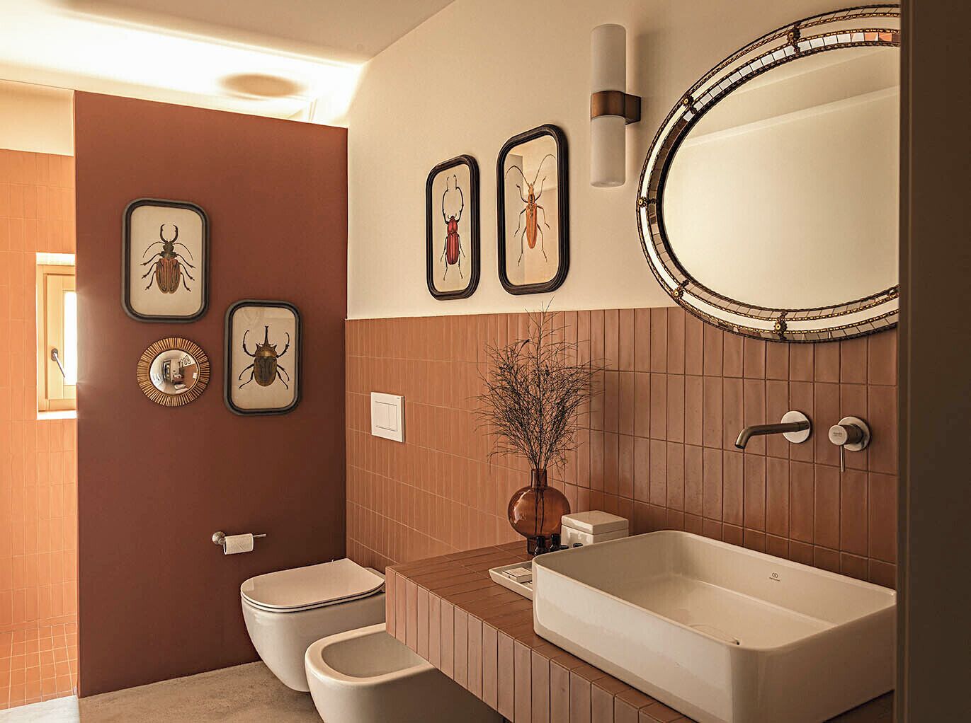 Un baño moderno con una bañera grande, un inodoro y un lavabo. En la pared hay cuadros enmarcados con imágenes de insectos.