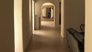 A corridor with high ceilings and arches, leading to a room with a large mirror and a sofa. - Dimora Santagatha  (Noto)
