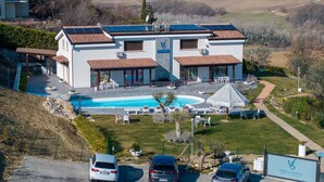 Uma villa moderna com piscina, área de estar externa e carros estacionados.