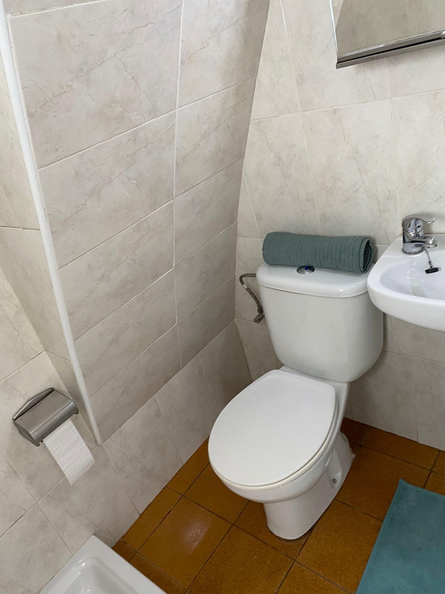 A bathroom with a toilet, sink, and a towel rack.