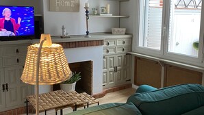 Una sala de estar con televisor, chimenea, sofá y lámpara.