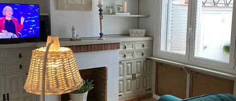 Una sala de estar con televisor, chimenea, sofá y lámpara.