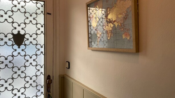 Una puerta con un diseño geométrico y un mapa mundial enmarcado en la pared.